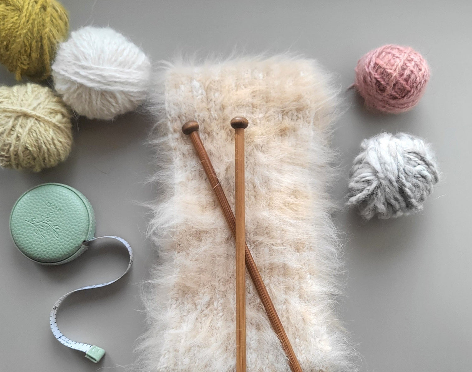 Garnnøster, strikket angoraskjerf og strikkepinner