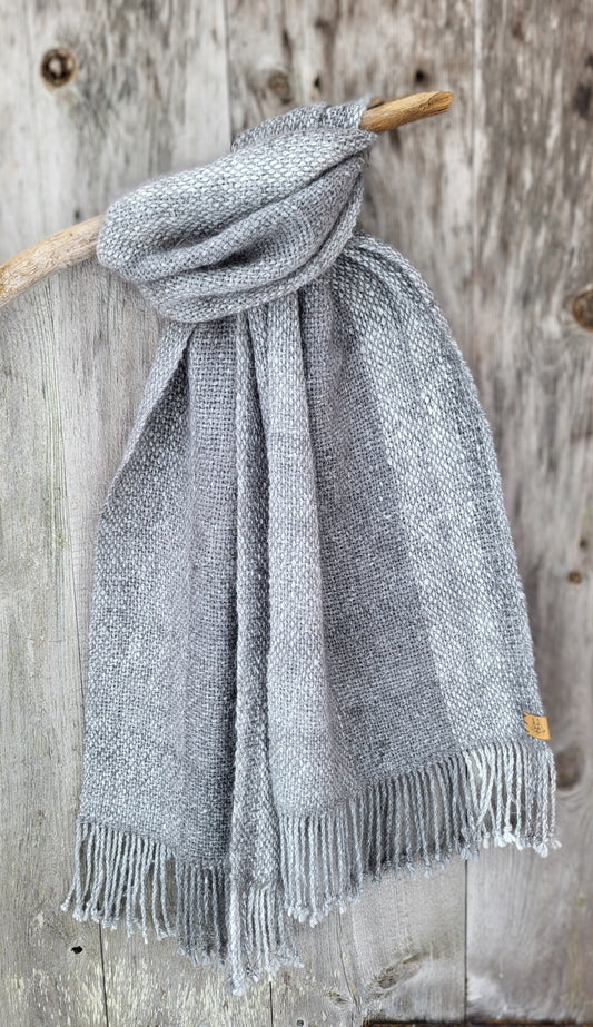 Håndvevd klassisk angoraskjerf drapert over trepinne med rustikk gammel dør som bakgrunn