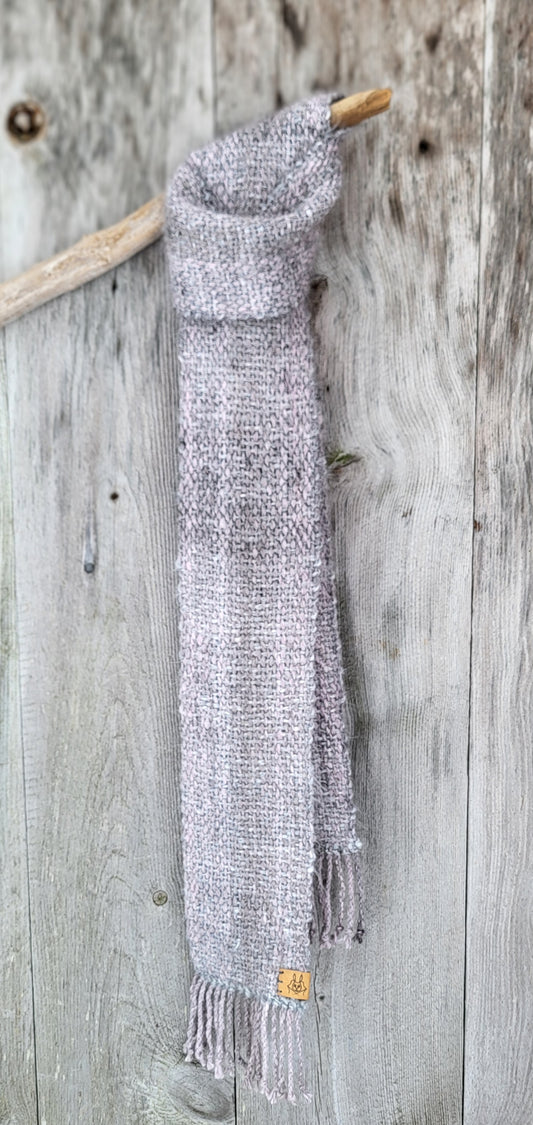 Håndvevd smalt klassisk angoraskjerf, plantefarget, drapert over en greit med gammel tredør som bakgrunn