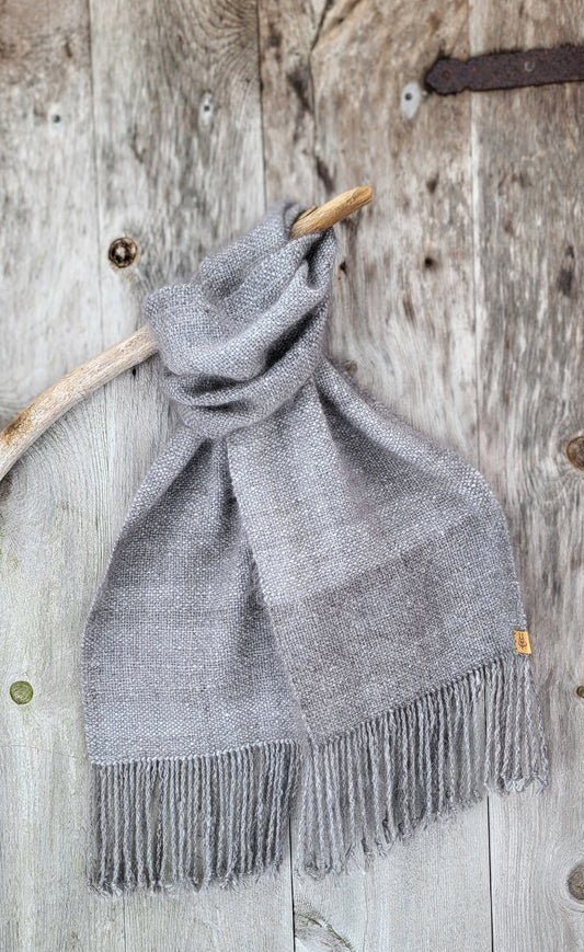 Håndvevd angoraskjerf klassisk drapert over trepinne med rustikk tredør i bakgrunnen